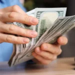 Dólar desacelera alta ante real com fluxo comercial positivo